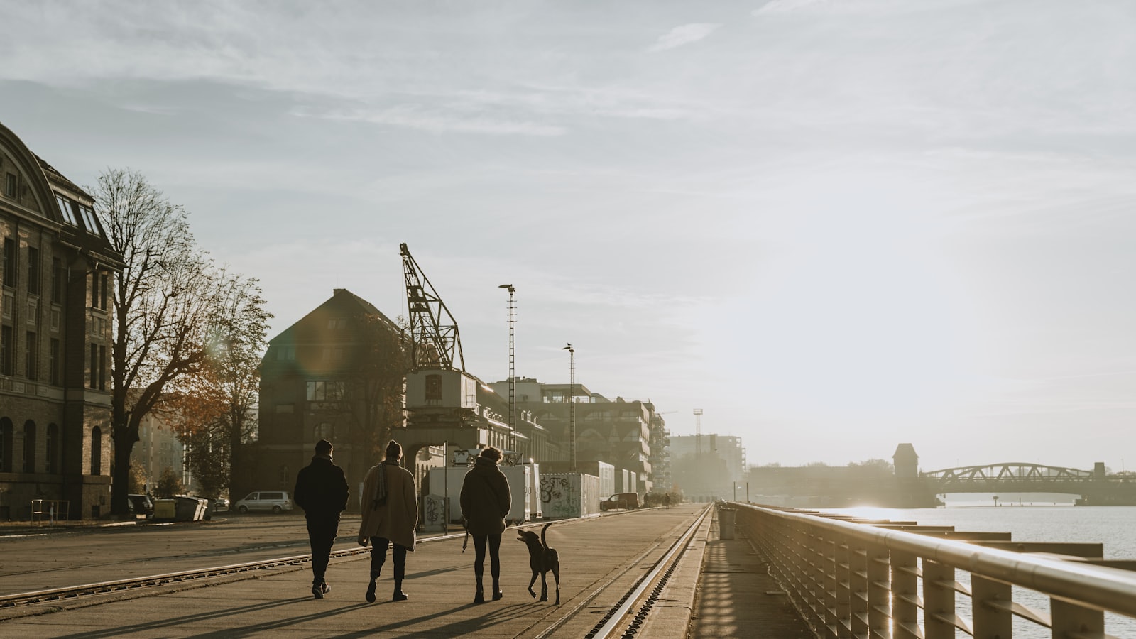 a group of people walking down a sidewalk next to a river
