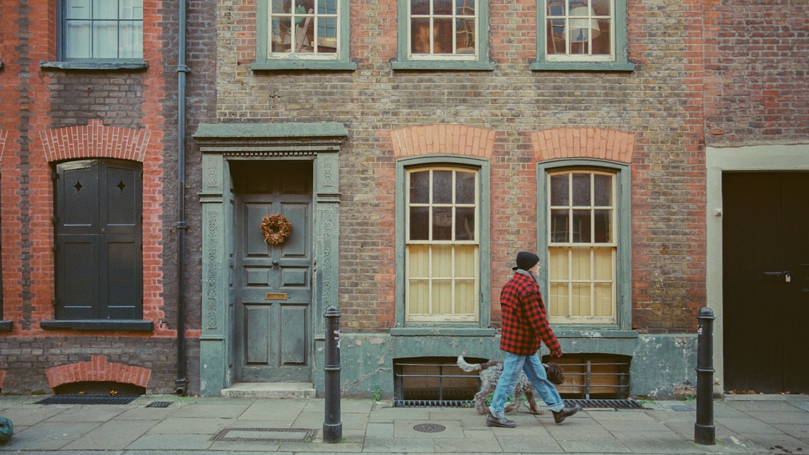 Man walks dog past brick row houses