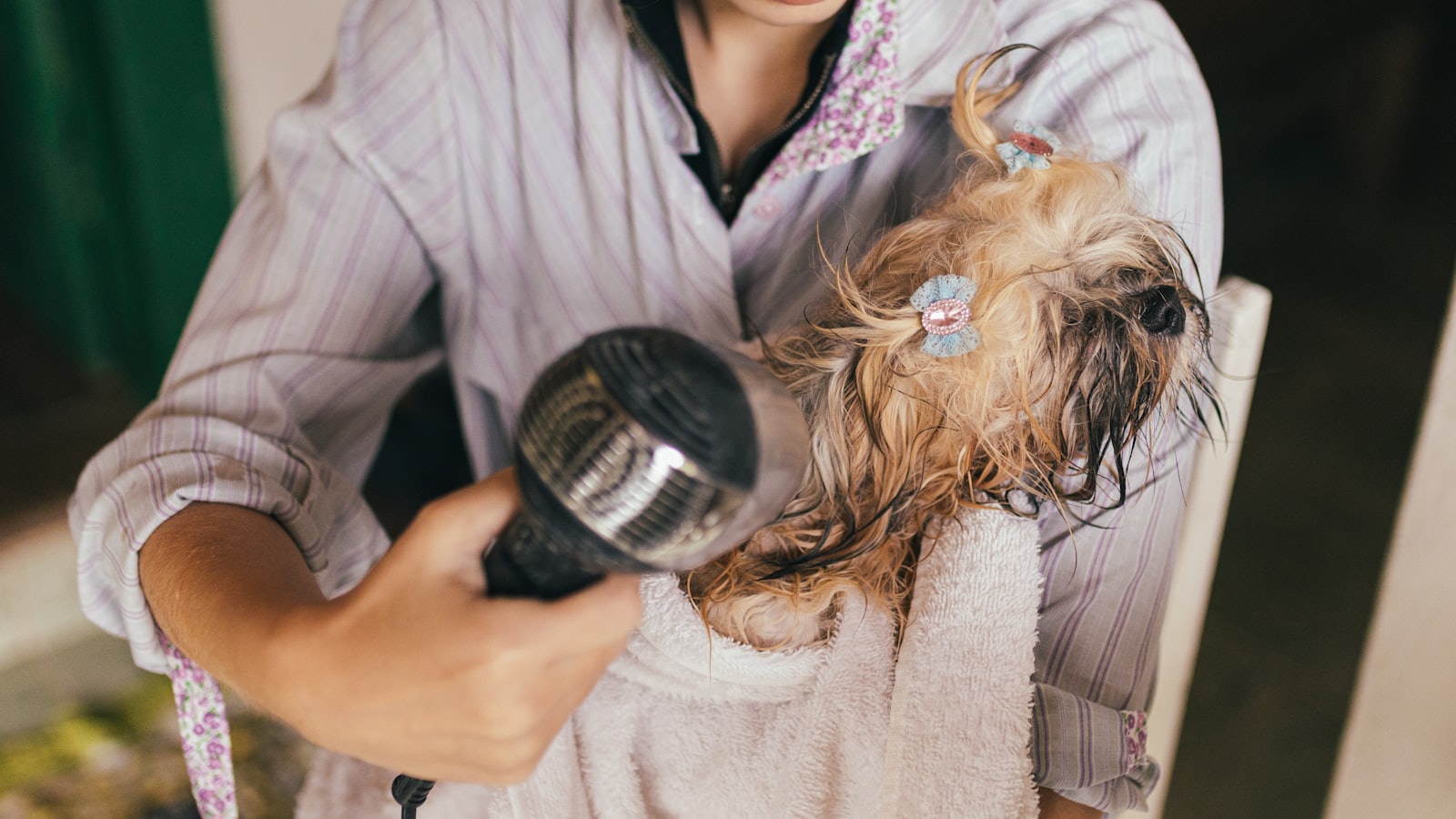 woman in pink bathrobe holding hair blower