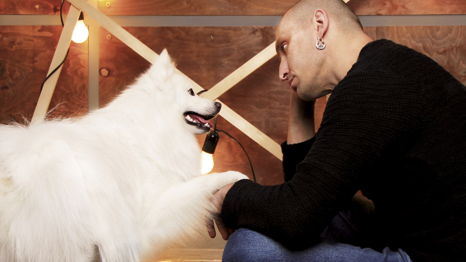 a man sitting on the floor petting a white dog
