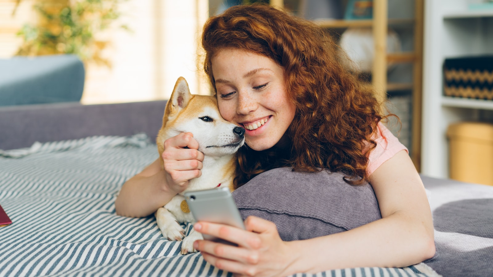 a woman laying on top of a bed holding a dog