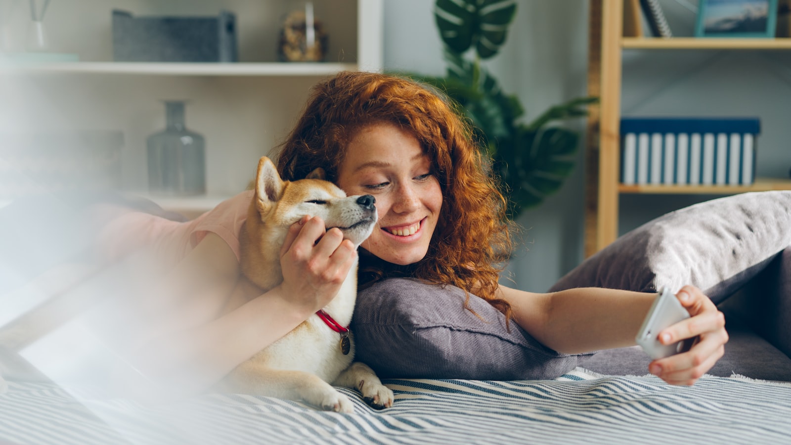 a woman laying on a bed holding a dog