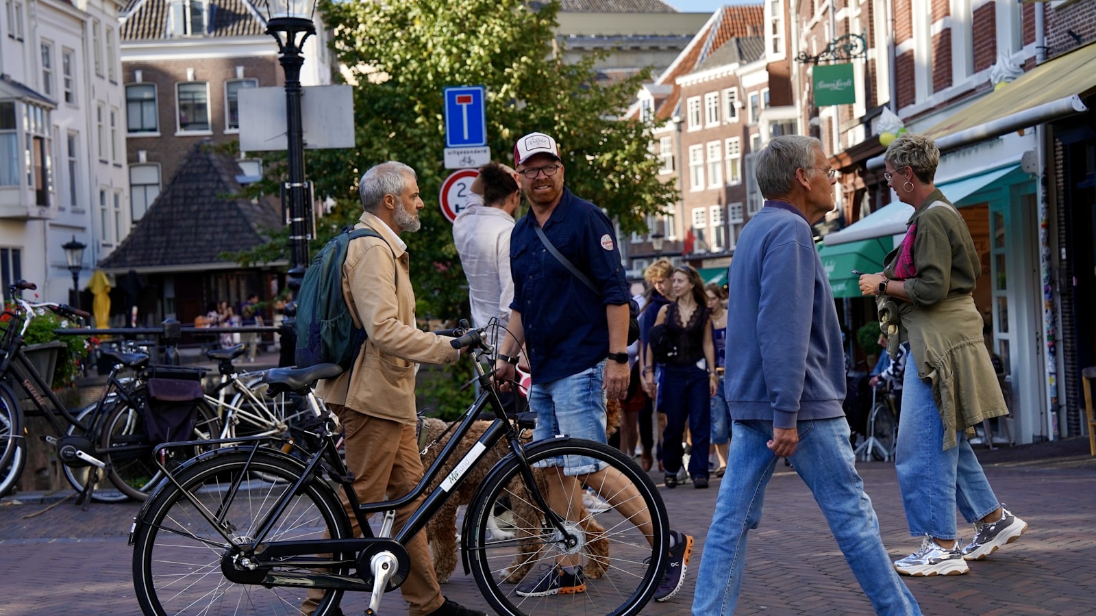 People walking and biking on a sunny street.