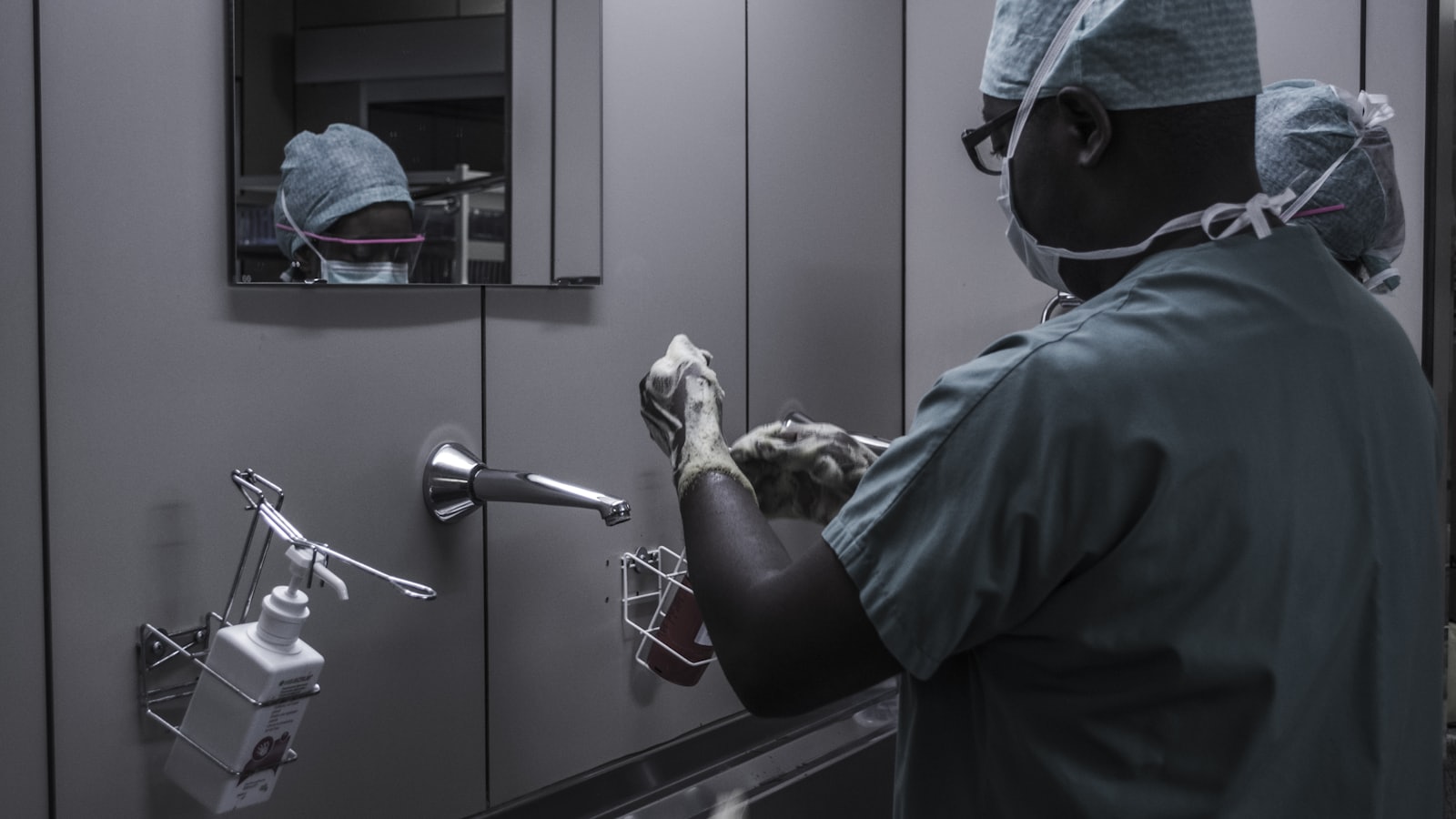 man wearing surgical suit near mirror